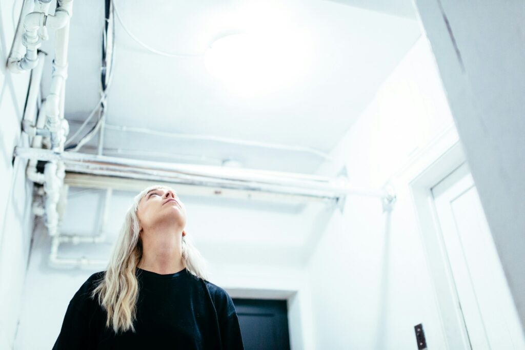A person looking at the ceiling, inspecting it for signs of water damage.